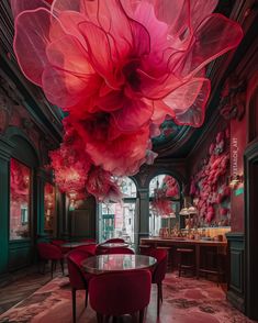 a dining room with red chairs and large pink flowers hanging from the ceiling above it