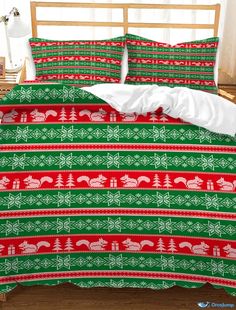 a bed with green and red christmas themed comforter set on top of a wooden headboard