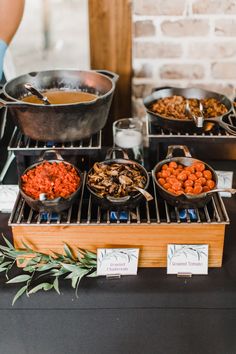 various foods are being prepared on a grill at a wedding or event in front of a brick wall