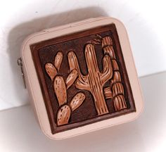 a brown and pink purse with a cactus design on the front, sitting on a white surface