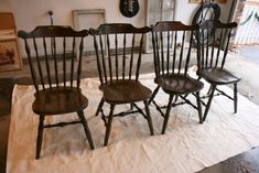 four wooden chairs sitting on top of a white cloth covered floor next to a window