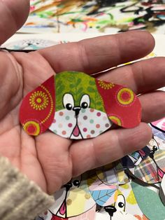 a hand holding a paper dog brooch in it's left palm, surrounded by many colorful stickers