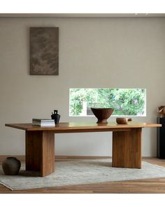 a wooden table sitting on top of a rug in a living room next to a window