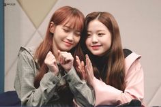 two young women sitting next to each other with their hands in the air and smiling