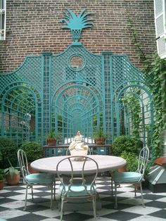 a table and chairs in front of a brick wall with an iron gate behind it