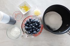 blueberries, sugar and other ingredients are being mixed together in bowls on the table