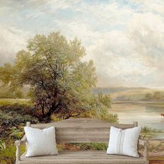 a wooden bench sitting in front of a painting on the side of a wall next to a body of water