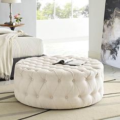 a white ottoman sitting on top of a rug in a living room next to a bed