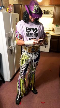 a man dressed in costume standing next to a refrigerator and looking at his cell phone