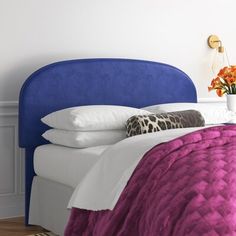 a blue headboard on a bed with white sheets and purple bedspread in a bedroom