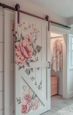 an open barn door with flowers painted on the side and behind it is a white dresser