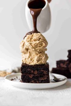 a piece of chocolate cake with whipped cream on top is being drizzled with chocolate sauce