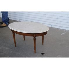 a white table sitting on top of a cement floor next to a person's feet