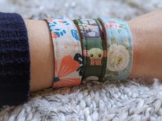 a close up of a person's arm with four different bracelets on it