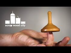 a hand holding a wooden object in front of a gray background with the words scrap wood city on it