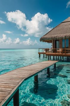 the water is crystal blue and has a wooden dock leading to an overwater hut