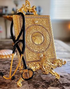 a pair of black and gold glasses sitting on top of a marble counter next to an ornate golden purse