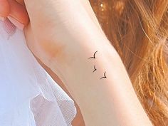 a woman's arm with a small bird tattoo on the left side of her wrist