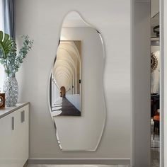 a mirror that is on the side of a wall next to a vase with flowers