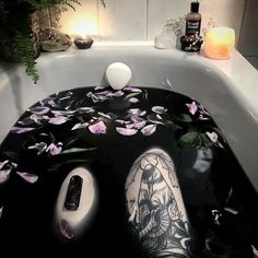 a bathtub with flowers on the floor and candles next to it, along with an electronic device