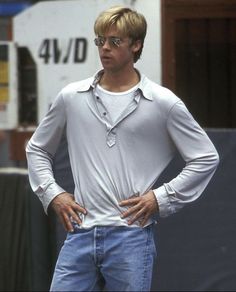 a man standing with his hands on his hips wearing glasses and a white t - shirt