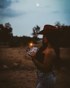 a woman wearing a cowboy hat holding a lit candle