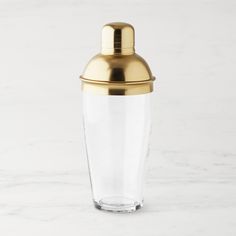 a glass with a gold lid sitting on a marble surface