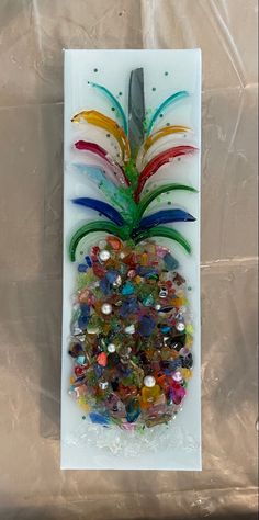 a glass pineapple with multicolored beads and a knife on it's side