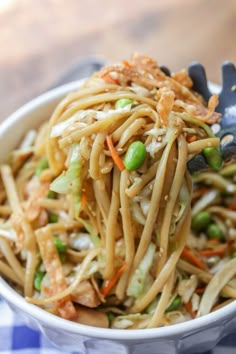 a bowl filled with noodles and vegetables on top of a blue checkered table cloth