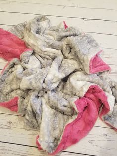 a pile of clothes sitting on top of a white wooden floor next to a red and gray blanket