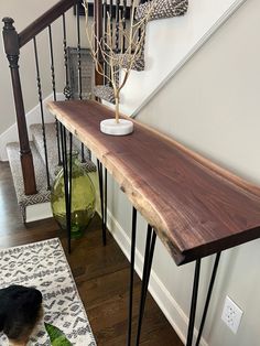 a dog laying on the floor in front of a wooden table with hairpin legs