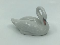 a white swan figurine sitting on top of a white table next to a wall