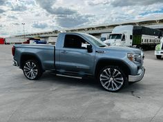 a silver truck is parked in a parking lot with other trucks and semi trucks behind it