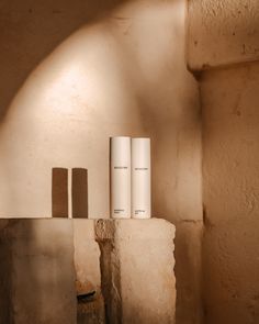 three rolls of toilet paper sitting on top of a cement block next to a wall