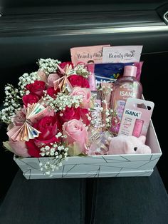 a pink and white box filled with lots of beauty products on top of a car seat