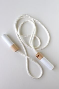 a white rope with two wooden ends and a rubber tube attached to it on a white surface