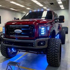 a large red truck is parked in a garage with lights on it's headlamps