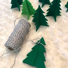 several green christmas trees are next to a spool of twine