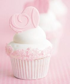 there is a cupcake with white frosting and a pink heart decoration on top