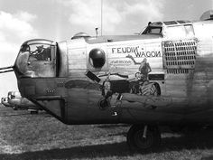 black and white photograph of an old airplane on the grass with clouds in the background