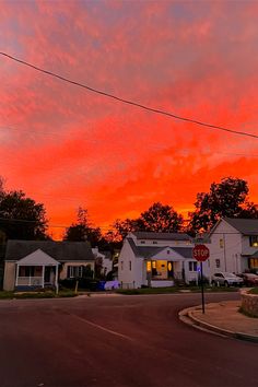 the sky is red and orange as the sun sets over some houses in this neighborhood