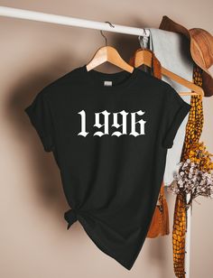 Travel back in time with our rad 1996 T-Shirt - a vintage-inspired gem that exudes nostalgia and cool vibes! Crafted with 100% Airlume combed and ringspun cotton, this tee offers unbeatable comfort, just like those cherished '90s memories. The light fabric (4.2 oz/yd²) is perfect for effortless style and a laid-back feel, whether you're hitting the streets or jamming to your favorite tunes. With a retail fit and tear-away label, this tee guarantees an awesome fit and maximum convenience. Embrace the spirit of 1996, a decade of iconic fashion and unforgettable moments! Please note: these tees are custom-made with love, so we can't accept returns. But trust us, this shirt will become an irreplaceable piece of your wardrobe! Ready to rock your '90s spirit? Snag your 1996 T-Shirt now and let y Vintage Black T-shirt For Birthday, Band Merch T-shirt With Graphic Print For Birthday, Vintage Slogan T-shirt For Concerts, Band Merch Graphic Print T-shirt For Birthday, Black Band Merch T-shirt For Birthday, Vintage Black T-shirt With Slogan, Emo Tshirt, Tattoo Tshirt, Date Tattoo