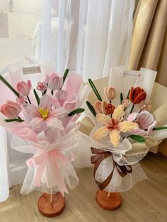 two vases filled with flowers sitting on top of a wooden floor next to each other