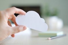 a person holding up a paper heart on top of a table