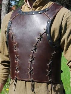 a man wearing a brown leather armor with black laces on his chest and shoulder