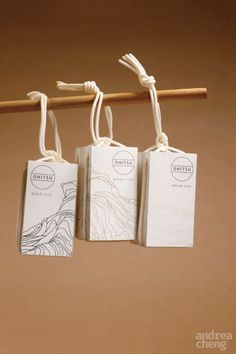 three tags hanging from a wooden stick with string attached to them, on top of a brown background