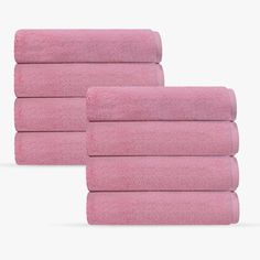 four pink towels stacked on top of each other in front of a white background,