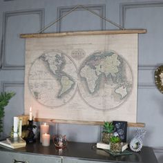 an old world map hangs on the wall above a dresser with candles and other decorations