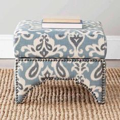 a blue and white ottoman sitting on top of a rug in front of a wall