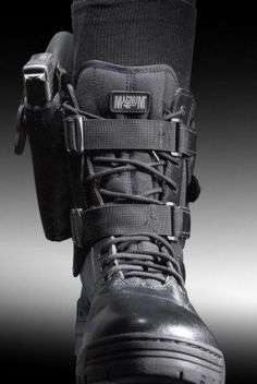 a pair of black boots with straps and buckles on the side, in front of a dark background